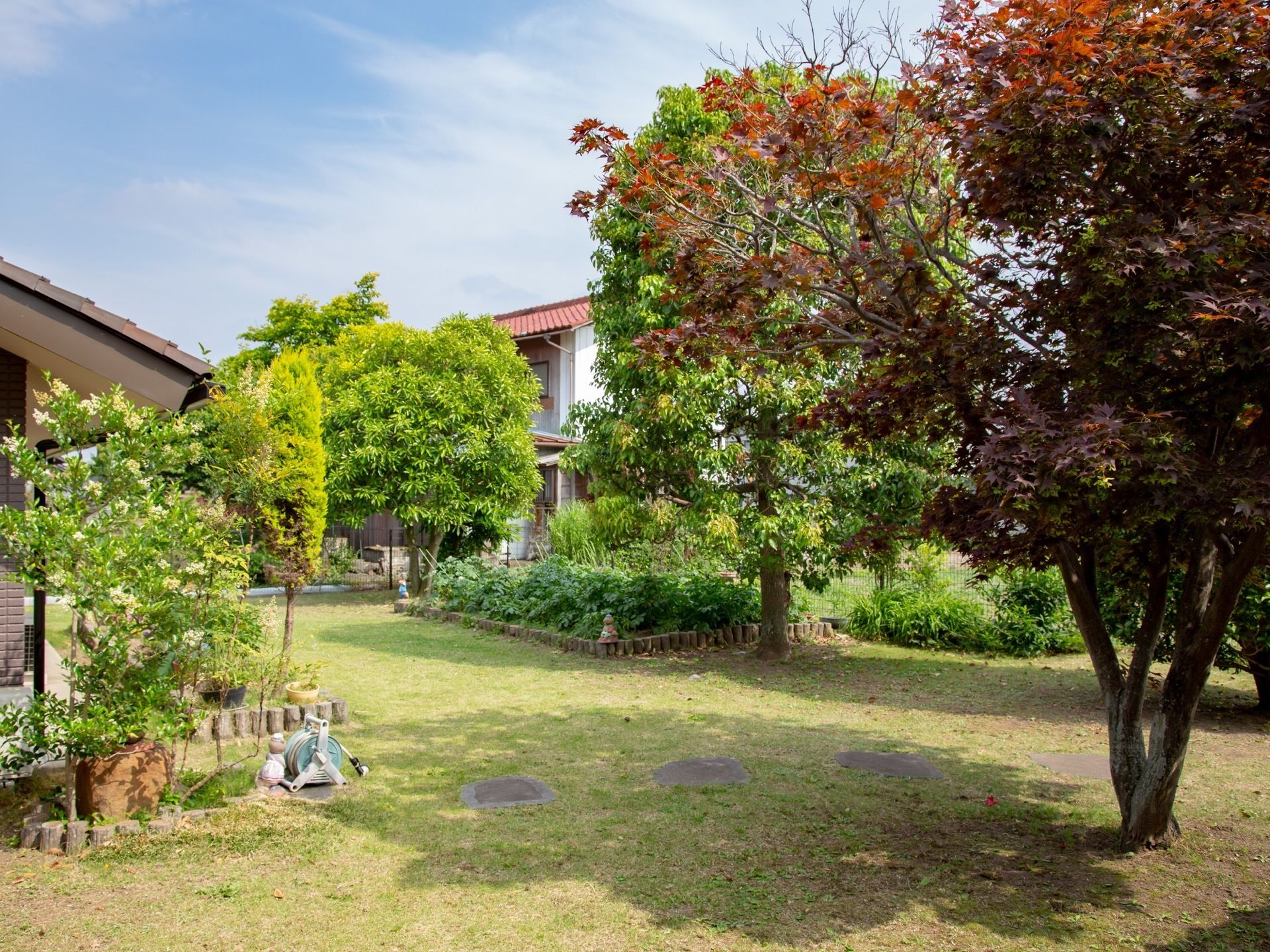 施設の敷地内には、庭がある。複数の木々が植えられており、家庭菜園が設けられている。水やり用のホースが置かれている。