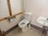 洗面台も完備された広々としたトイレである。Ｉ型や水平型の木製手すりが壁に設置されている。扉は開閉が楽なスライドドアになっている。