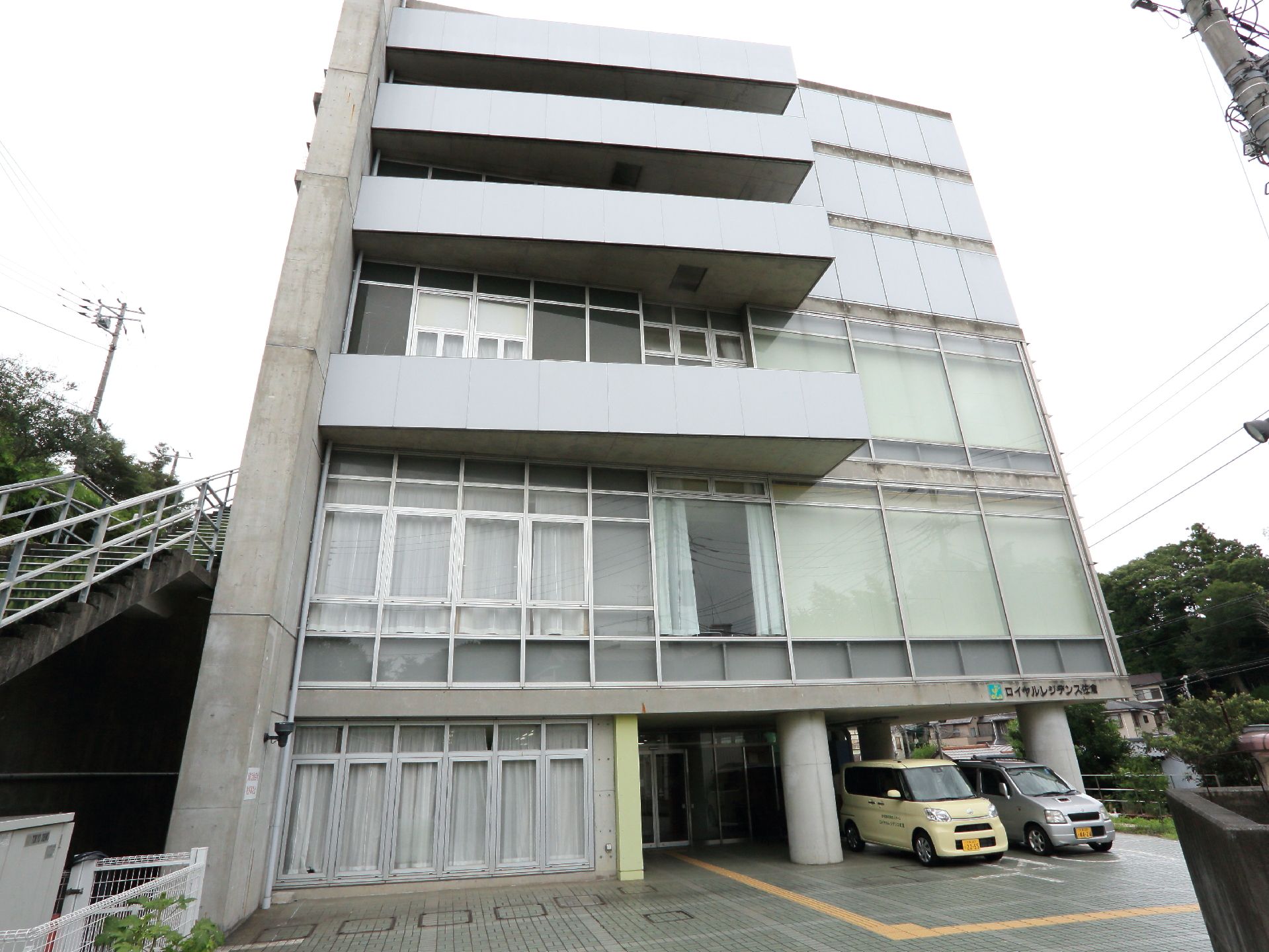鉄筋コンクリートで構造されている施設は6階建てになっている。1階の屋根部分には車の駐車スペースになっていて、車が何台か止められている。