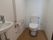 壁面が花柄の壁紙で、フローリングの洋式トイレがある。壁に手すりがついている。独立した手洗い場がある。