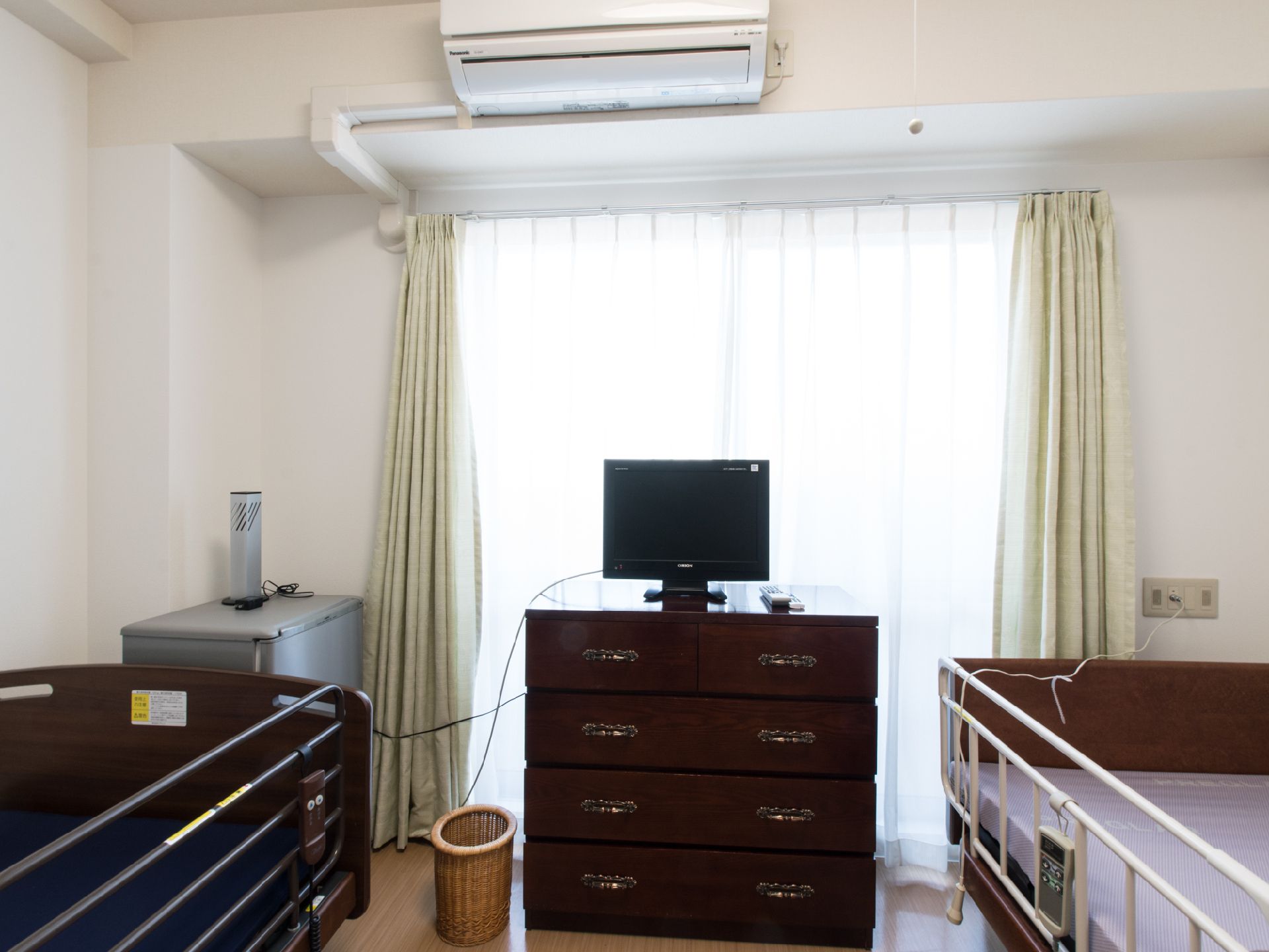 部屋の両サイドに電動ベッドがある。チェストの上にテレビが置いてある。エアコンが完備の部屋である。緊急時呼び出しブザーがある。