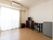 エアコンのあるフローリングの部屋で、ベランダ窓がついていて陽光が差し込んでいる。壁際にチェスト、机、いすなどが置いてある。