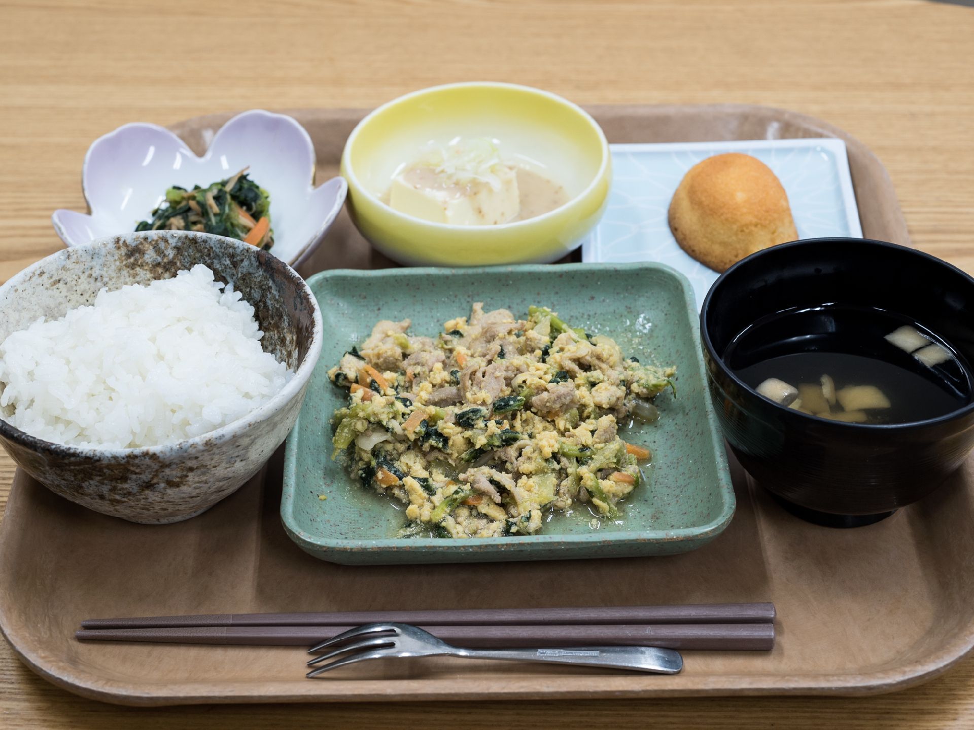 お盆上には、フォークや箸、副菜や主菜やデザート等いろいろな料理がのっている。施設では利用者の献立を職員が考え提供している。