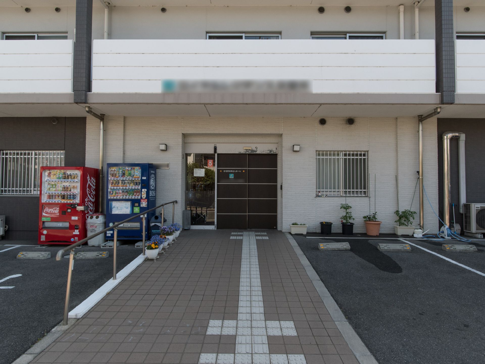玄関の周囲にはプランターが置いてある。アスファルトで整備された駐車場があり、玄関そばで車をとめることができるので、乗降が楽である。