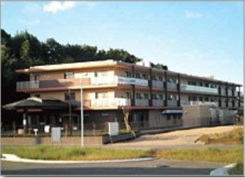 フェンスで囲まれた広い敷地内に建っている三階建てのベランダがある建物