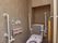 トイレには、フタのついていない便座が設置されている。壁には、３か所で固定されている手すりが付けられており、トイレットペーパーは入っていない。