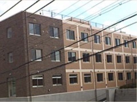 電線が何本もある向こう側に建っている、茶色い三階建ての建物