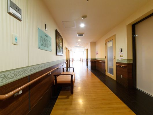 3人が座れるベンチのようなものがあり、その後ろには長い手すりが設置されている。右手にはいくつかドアが見える。"