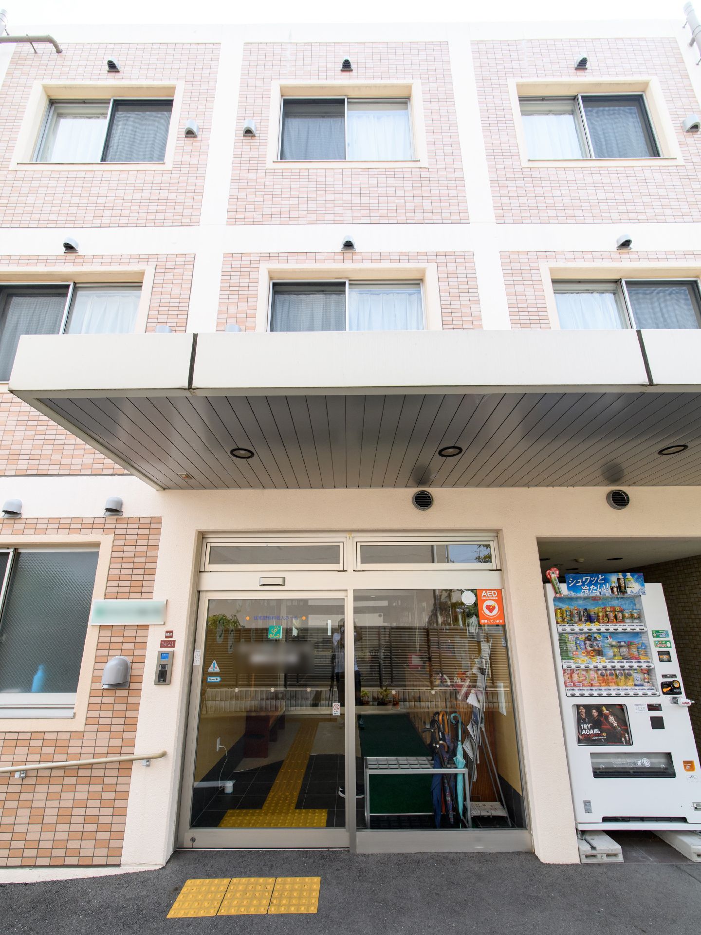 雨除け用の屋根に覆われた入口部分に自動ドアがある。屋根の上側にはいくつかの窓が見え、個室ごとに区切られている。