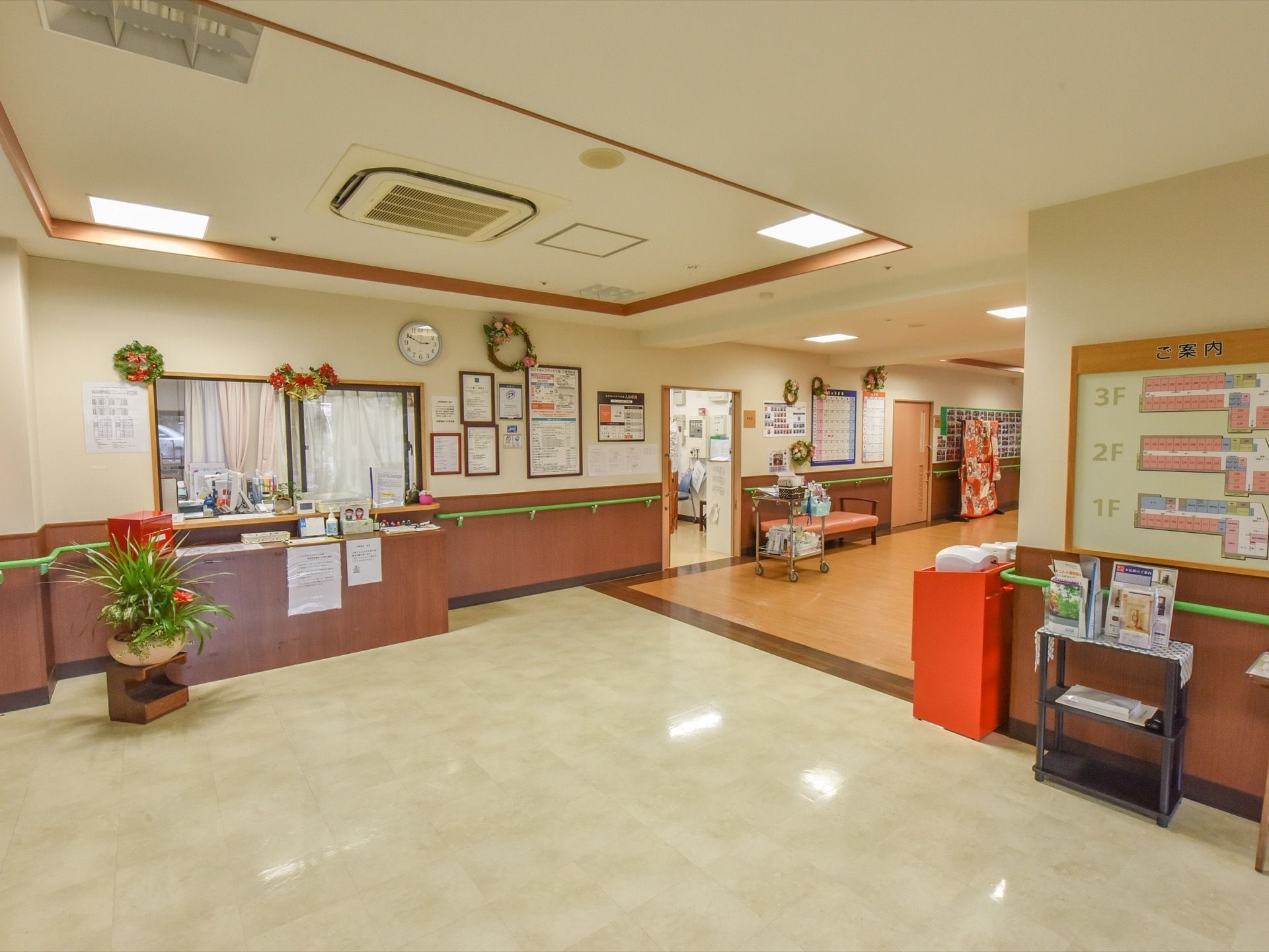 玄関から入って真正面に受付窓口が位置している。カウンターの足元には台の上に観葉植物の鉢植えが飾られている。