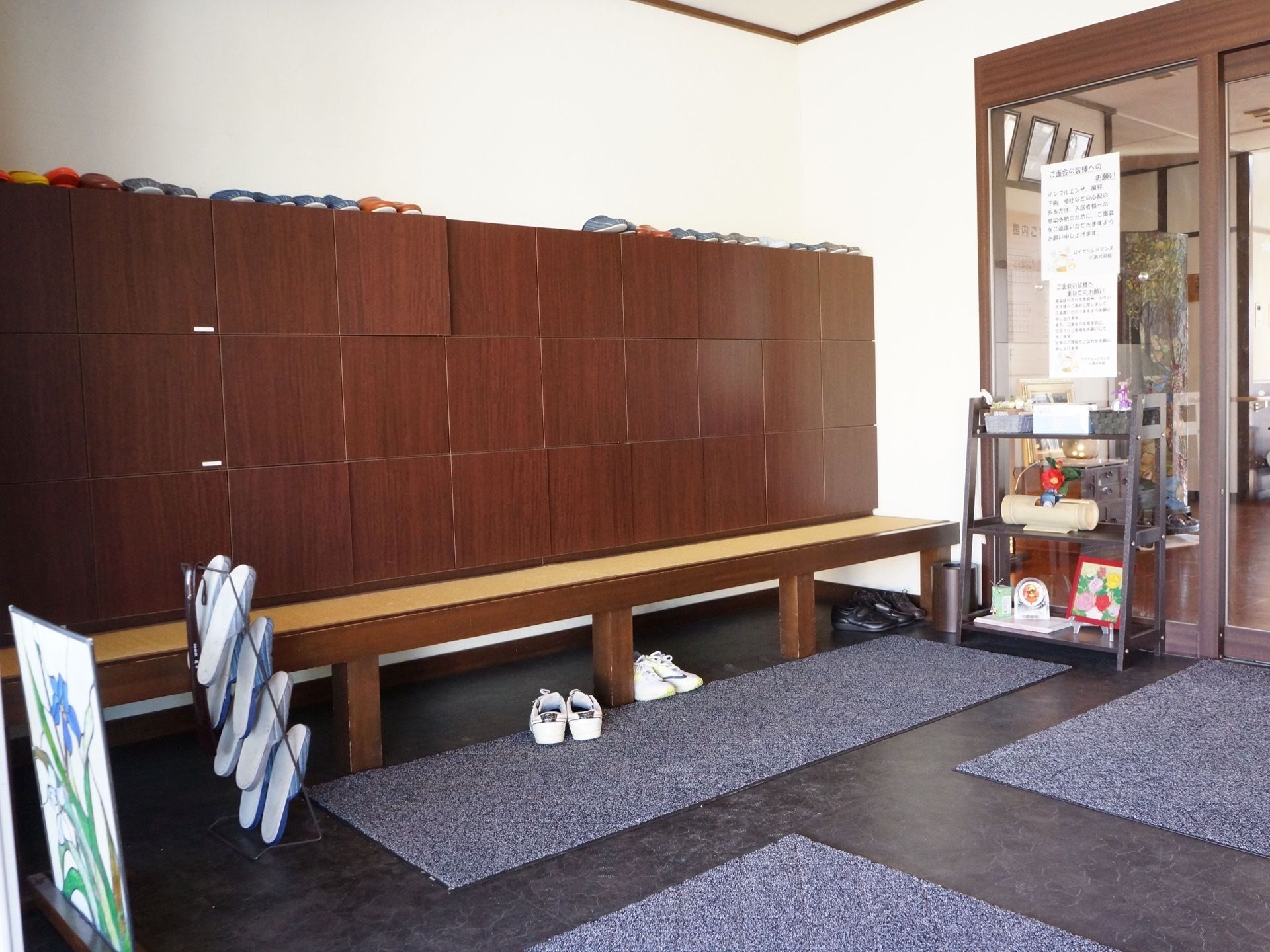 茶色い箱型の靴箱が壁一面に設置されている。靴箱の前には細長いベンチがあるので、座って靴の脱ぎ着ができるて安心である。