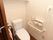 ハンドルがついたスライド式のドアのトイレで、壁付の棚が設置してある。手すりが壁についていて、立ち居が楽である。