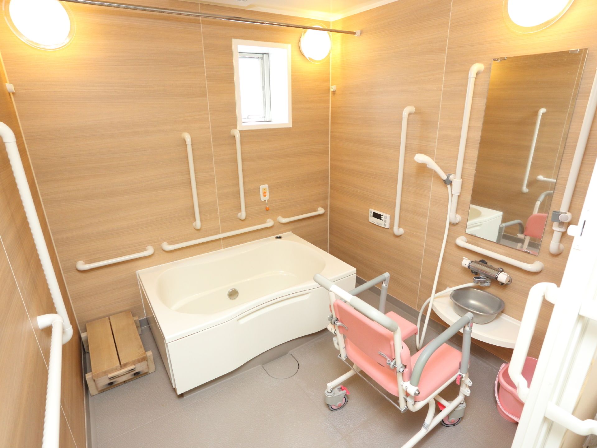 お風呂の壁には手すりがついていて、入浴がしやすく工夫がしてある。段差を低くするために、台が設置してあり、それを使って湯船に入ることができる。