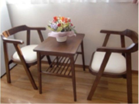 花が飾られている小さなテーブルと二脚のイスが置かれた部屋の一角