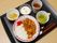 カレーライスの他、和え物、汁物、デザート、箸休め、お茶を盆にのせて提供している。食事の品数が豊富である。