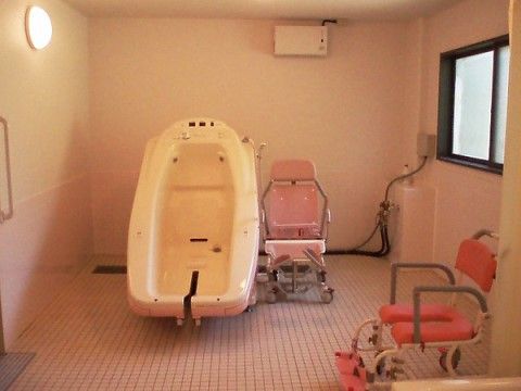 タイル貼りの広い浴室に設置されている、入浴介助の装置と入浴用車椅子