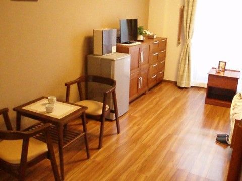 壁際に収納家具、冷蔵庫、小さなテーブルと椅子が設置されている居室
