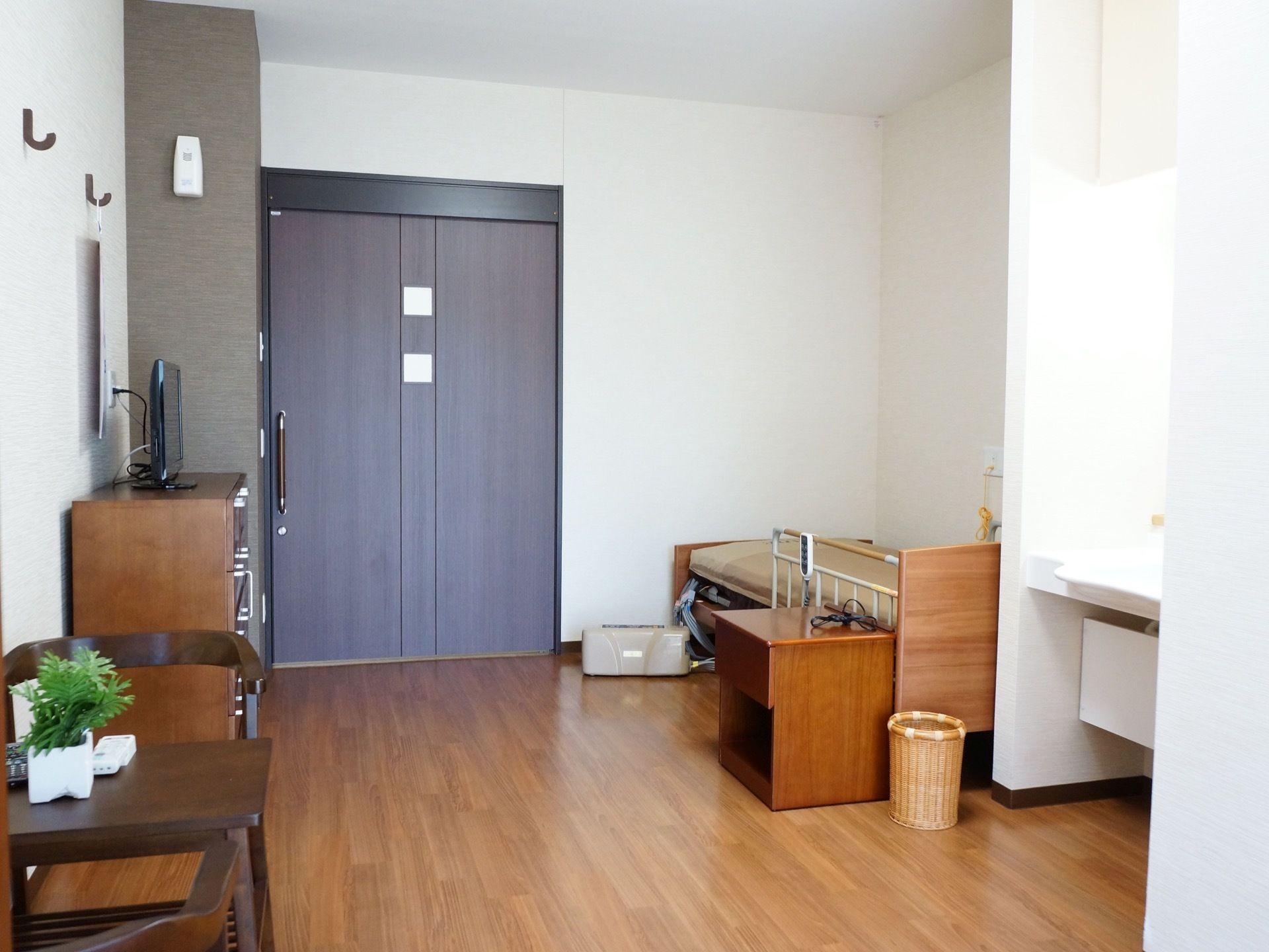 室内から居室入り口側を見たところ。水回りではなく入居者様用の介護ベッドがドア近くにレイアウトされている。