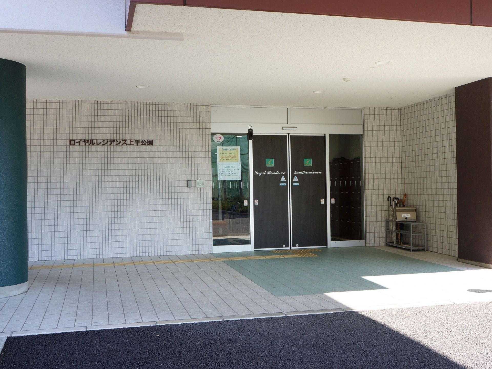 エントランスを外から見たところ。自動ドアの左側の壁には呼び鈴、さらに左に施設名のロゴが取り付けられている。