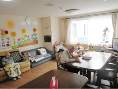 テーブルセットは部屋の中央に置いてある。壁際に並べたソファーには、膝掛けをしてリラックスしている入居者様がいる。