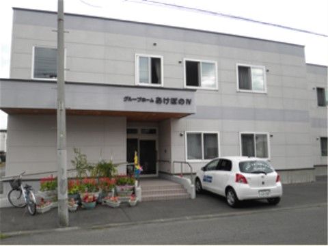 ２色のグレーを使い分けた外装のホーム。玄関前には、施設名を記した屋根が付いている。屋根の下に階段とスロープがある。