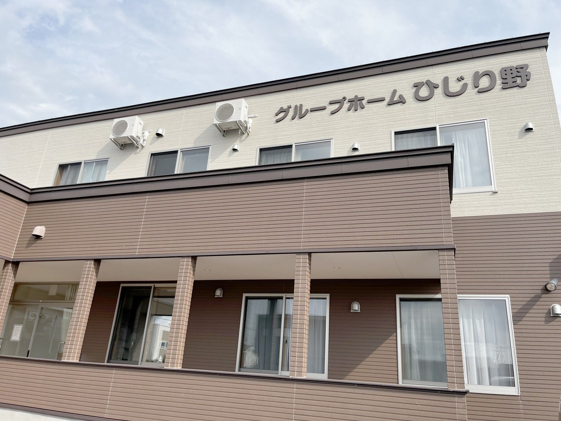 車椅子に座った高齢女性と隣りに寄り添う女性ヘルパー