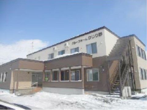 ２階建てで採光十分な大きな窓があり、白と茶色の明るい配色の建物である。屋外階段が設置されており、建物周辺には雪が積もっている。