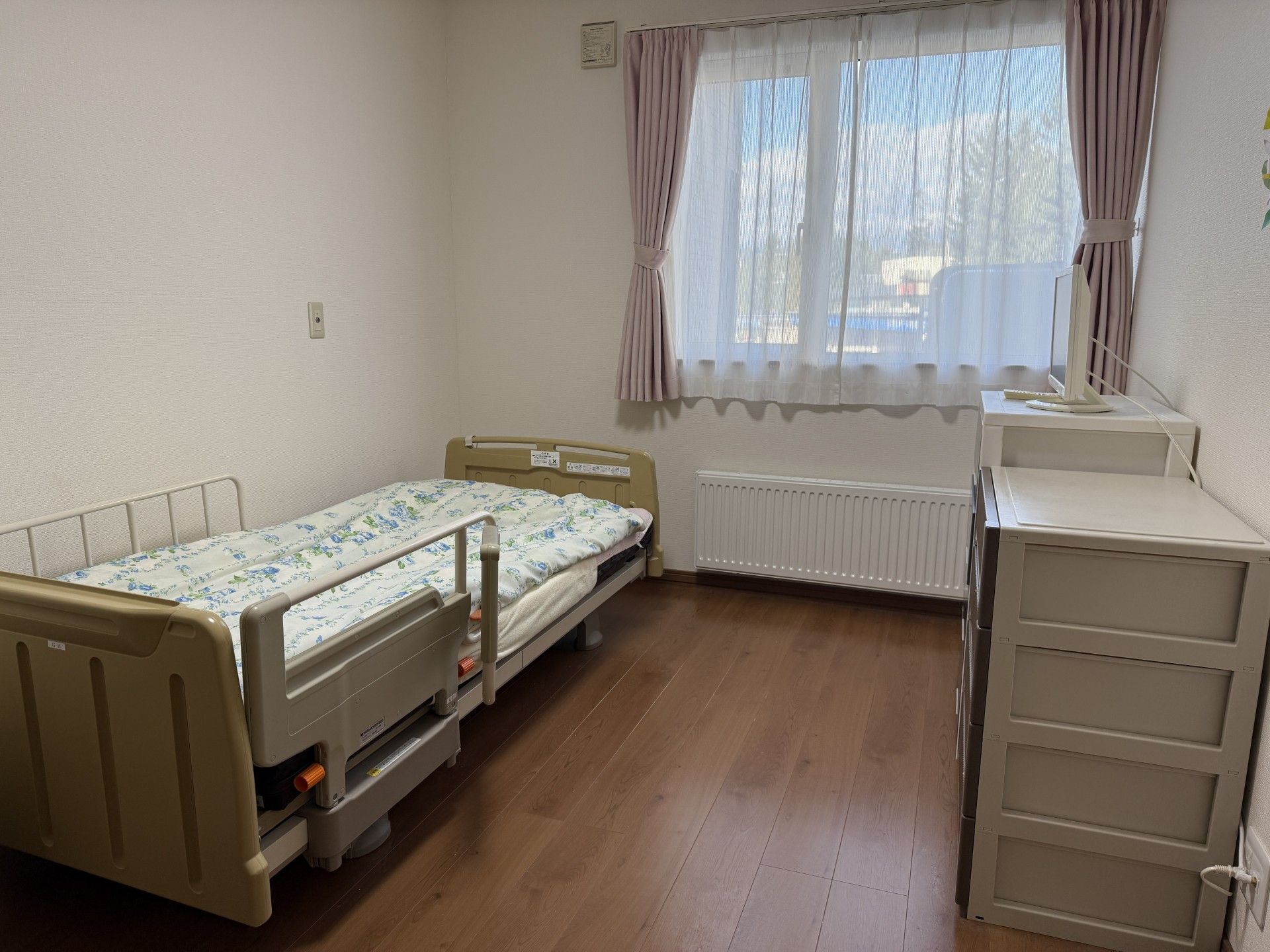 木陰にいる車椅子に座った高齢男性と介助をする女性ヘルパー