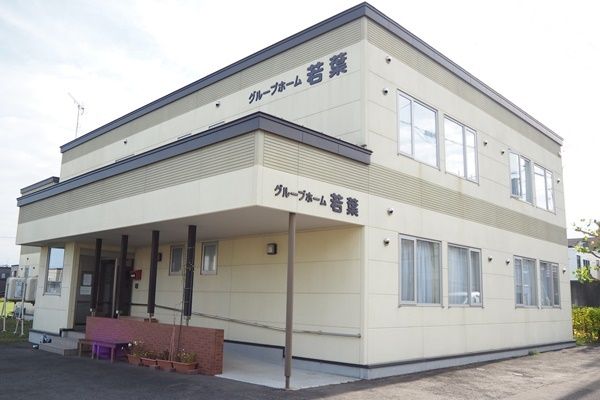壁の色はクリーム色で屋根周りだけが黒で塗られており、アクセントになっている。玄関にはスロープと長いひさしが設置されている。