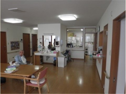 木製のダイニングテーブル、椅子などが置かれている。ゆったりとしたスペースで、奥はキッチンになっている。