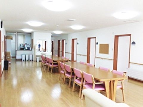 居室の扉がいくつか見えている。壁には手すりが設けられている。奥にはキッチンが設置されており、ゴミ箱が３個見える。