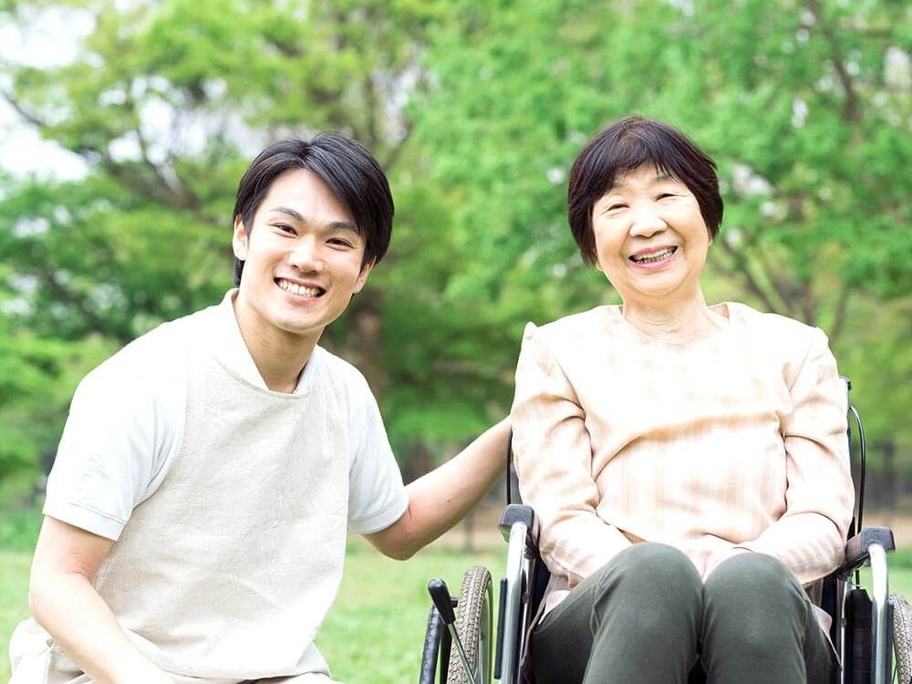 車椅子に座った高齢女性と介助をする男性ヘルパー