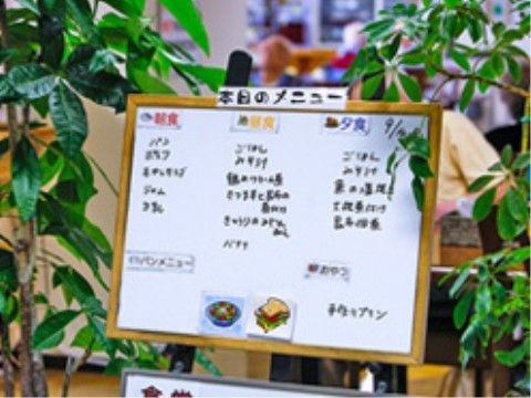 観葉植物の隣に置かれた、本日のメニューが書かれているホワイトボード