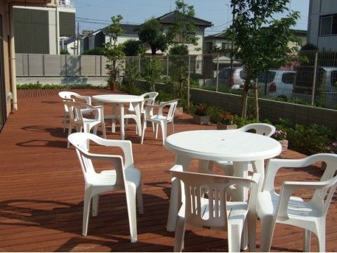 プランターや植栽があるウッドデッキに置かれている白いテーブルと椅子