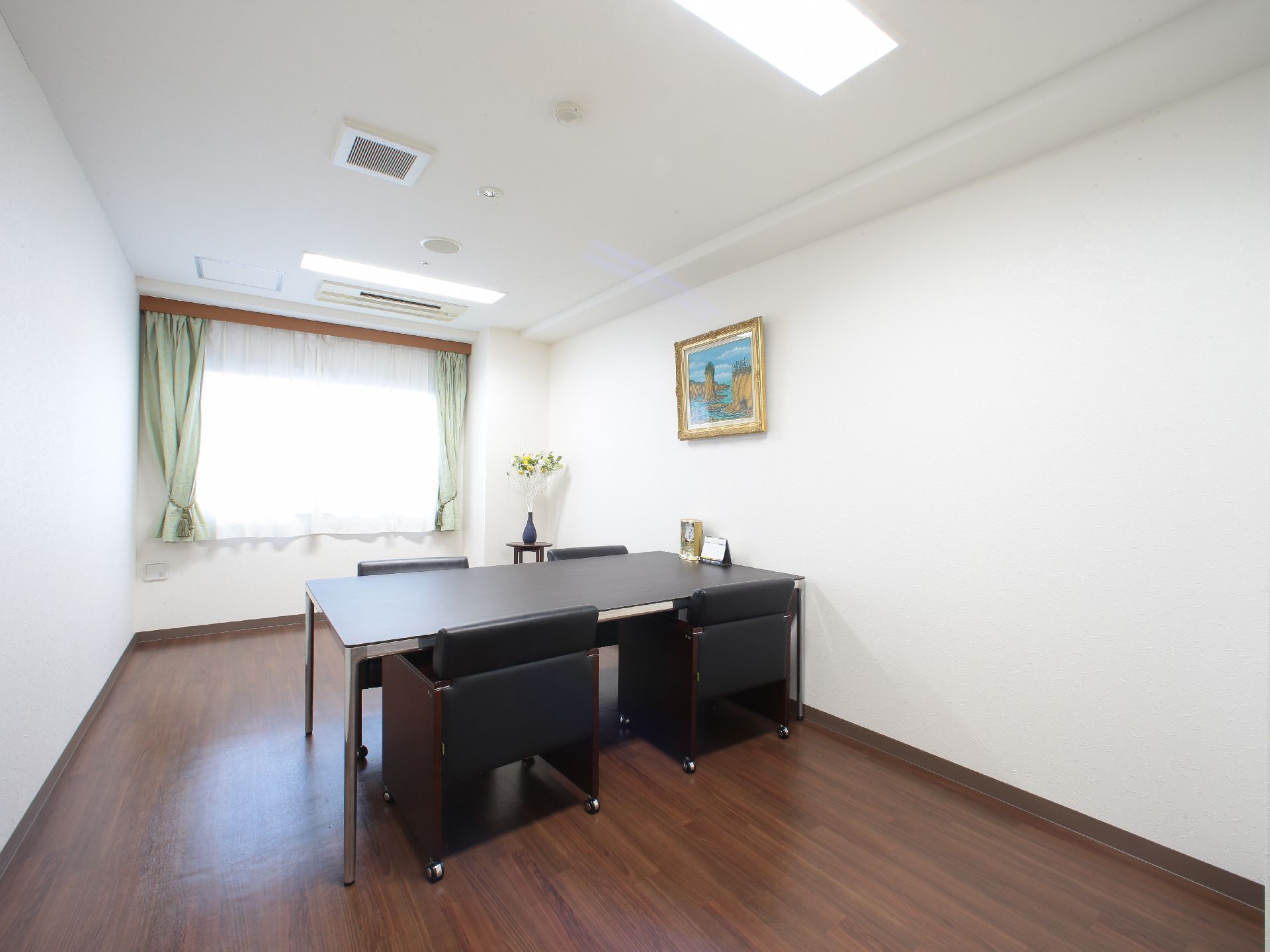 室内の中ほどに黒い大きなテーブルが一台おいてあり、椅子が四脚並べてある。角にコーナーテーブルがあり、花瓶が載っている。