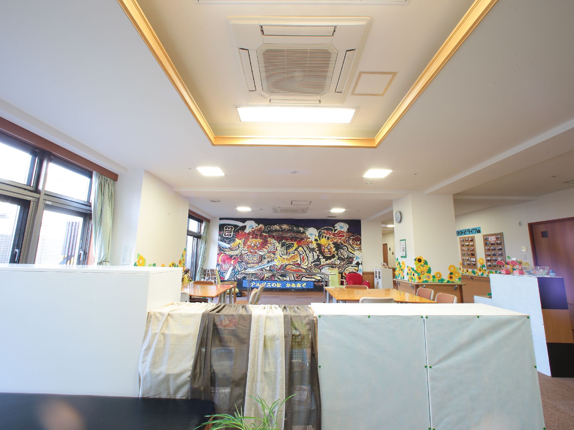 壁一面に絵が飾られている。脚力をつけるための器具がその前に設置してある。机が二台、椅子が五脚以上置いてある。