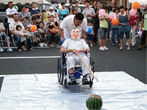 観客に見守られる中、スタッフのサポートで車椅子に乗り、すいか割りをする入居者様