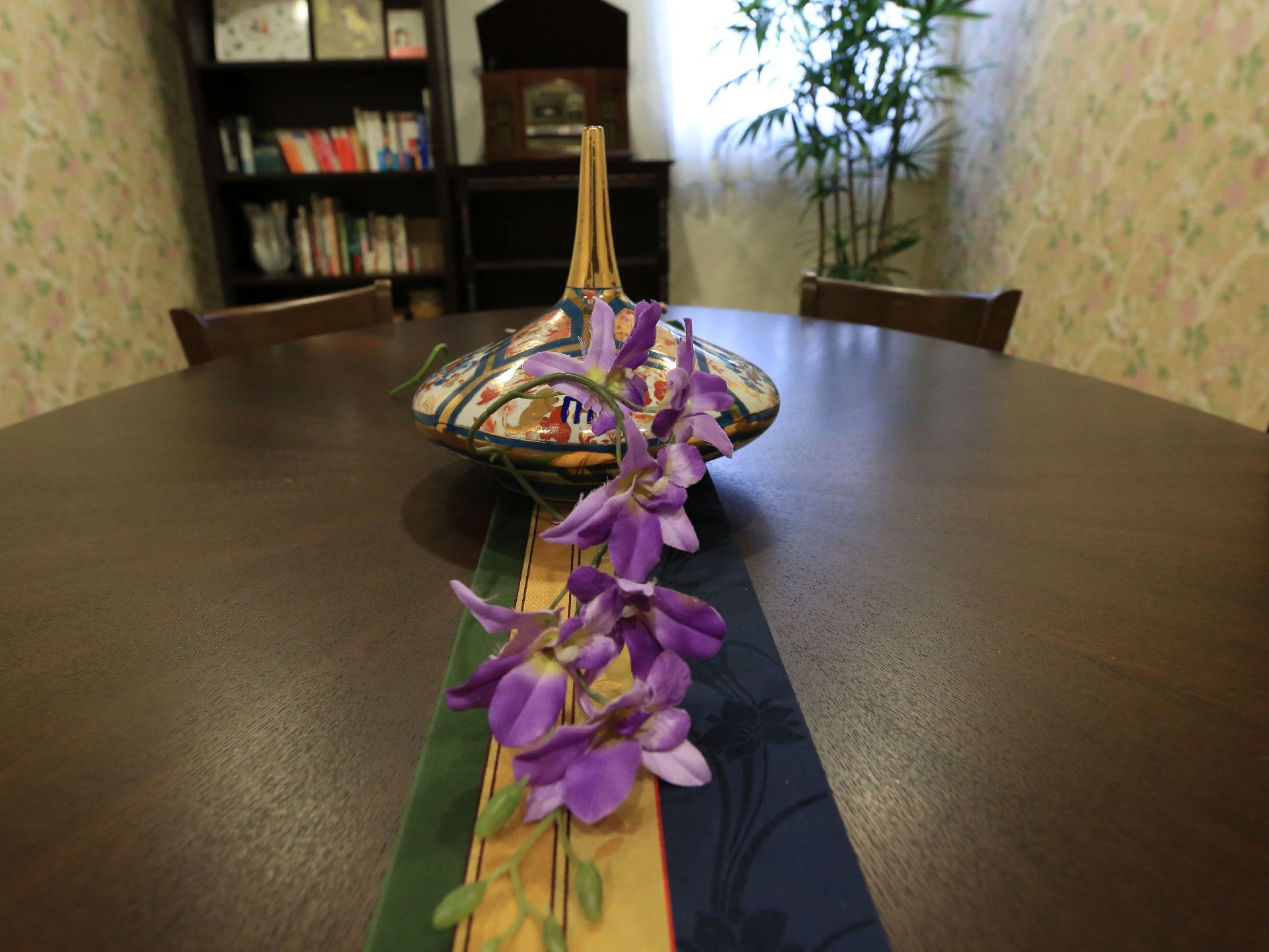 丸いテーブルの上に陶器の置物とテーブルクロス、蘭の花が置かれている。全体的に落ち着いた、大人の雰囲気が漂う。