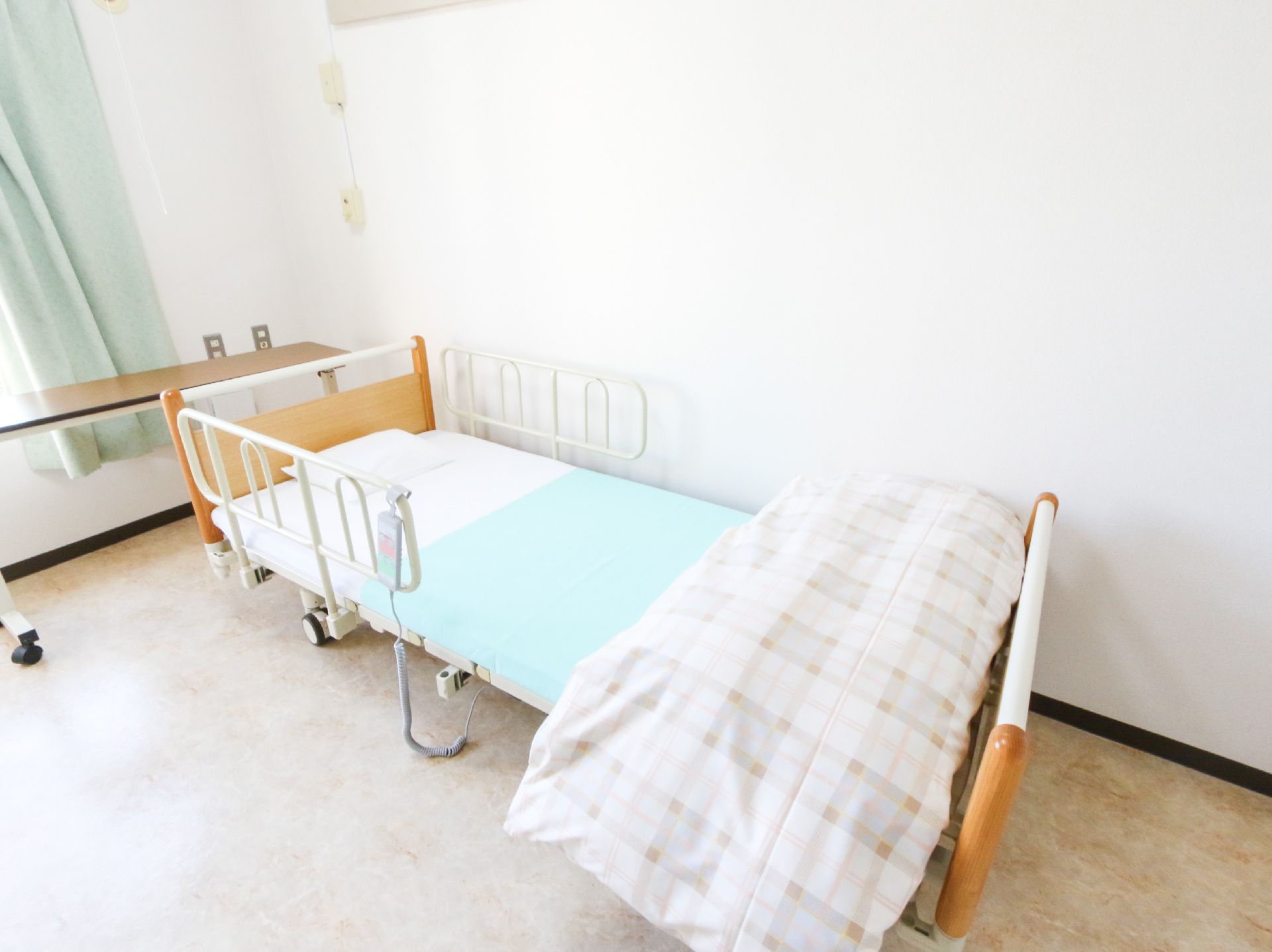 窓から日差しが入り、介護ベッドが置かれている居室