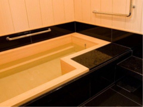 艶やかな黒い石材に囲まれて、ヒノキの浴槽がある。浴槽の中には手掛かりになるへこみがあり、周りには手すりがある。