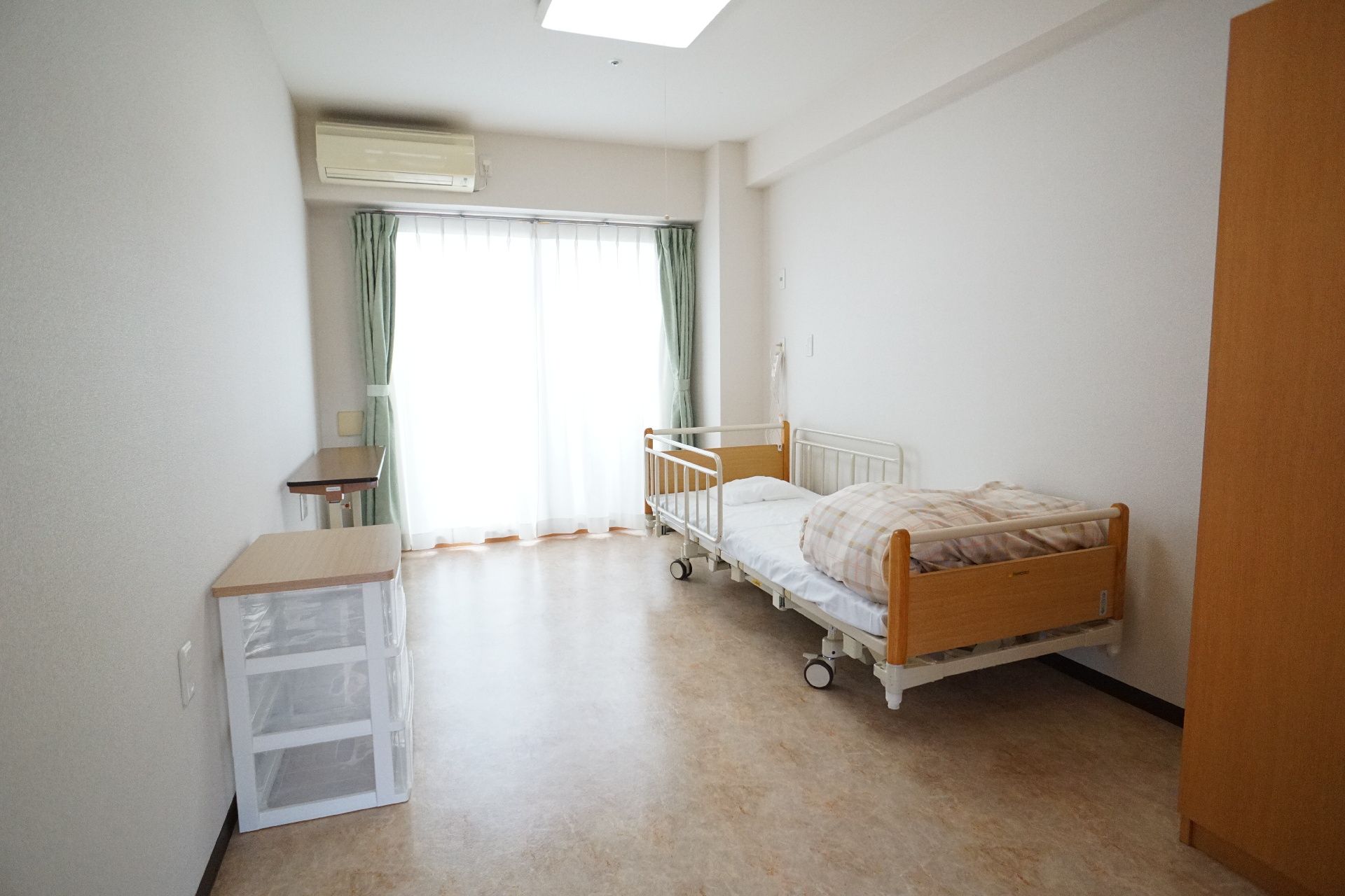 窓から日差しが入り、備え付けの介護ベッドなどがある居室
