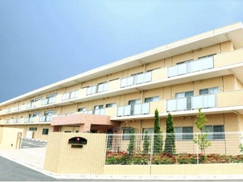 3階建ての建物と建物前にある駐車場と花壇