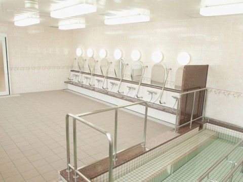 大きな浴槽と複数のシャワーが設置された大浴場