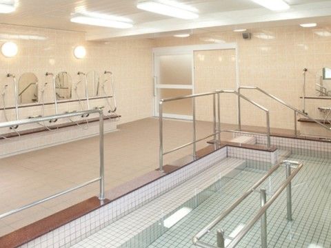 大きな浴槽と複数のシャワーが設置された大浴場
