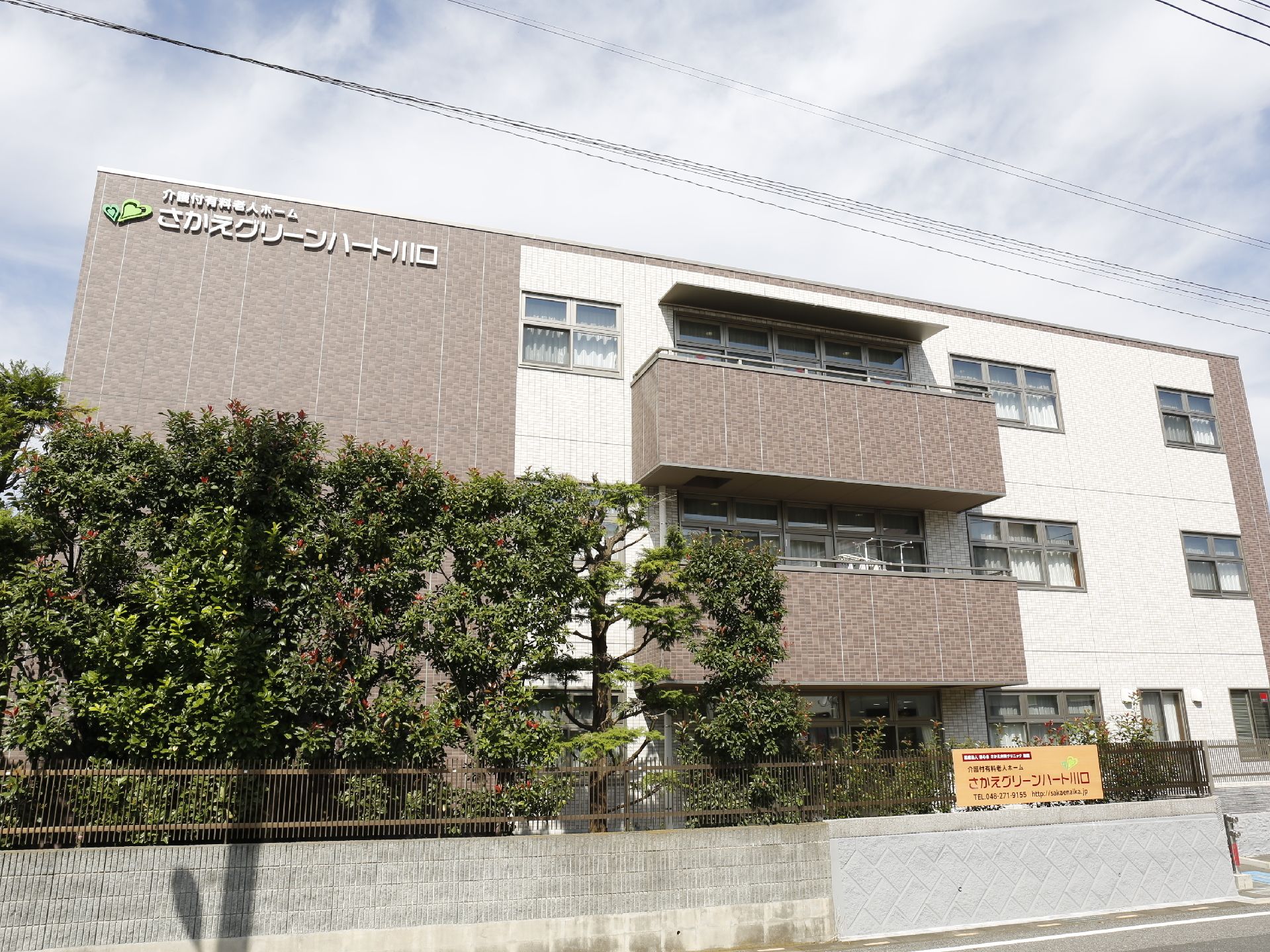 3階建ての建物の上方に大きく施設名が書かれているので、遠くからでもすぐに見付けることができる。手前には背の高い木の植え込みがある。