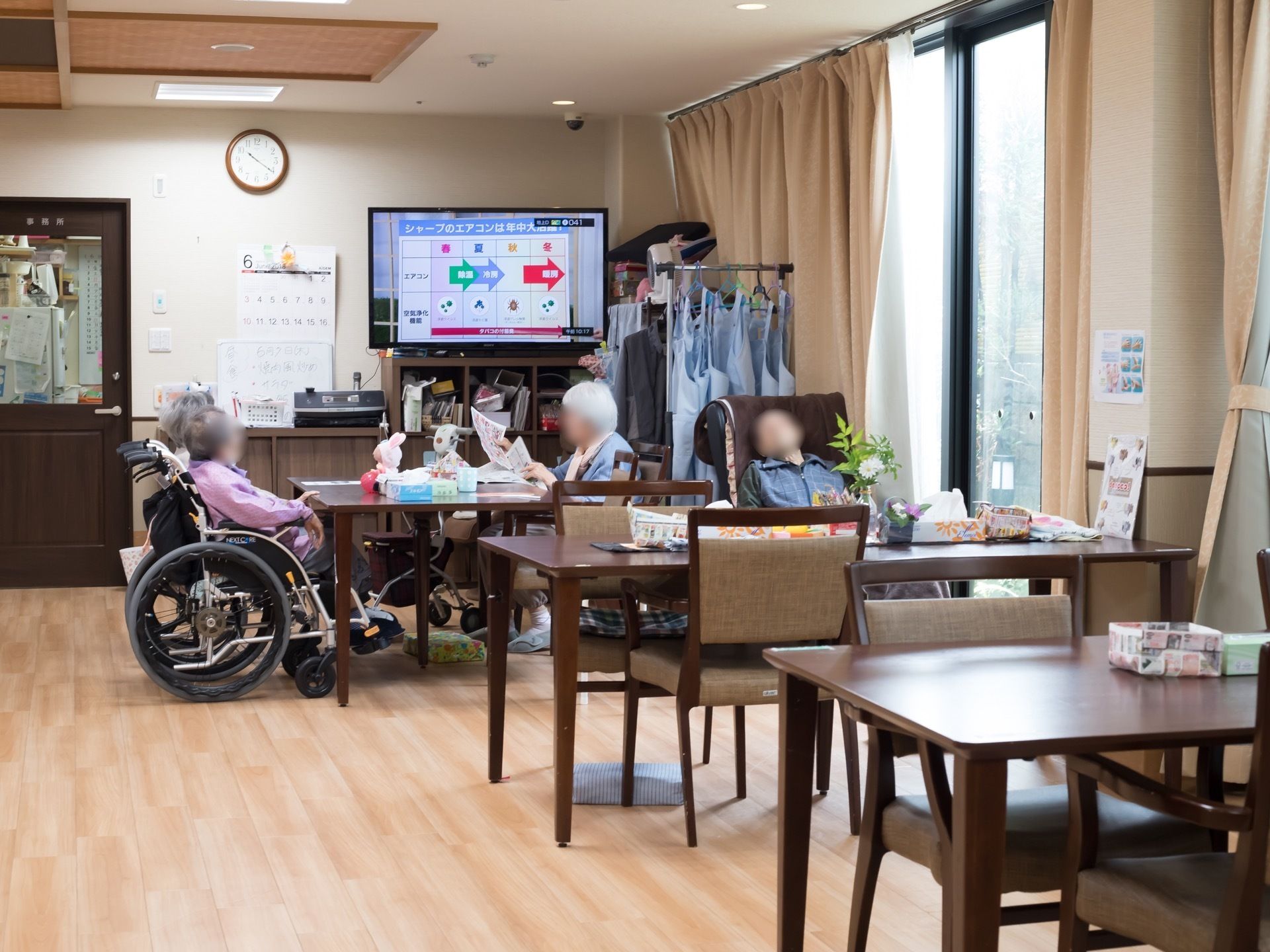 白いフローリングに黒いテーブルが配置されている共有のリビング。新聞を読んだりテレビを見たり、思い思いの時間を過ごせる。