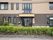 施設建物の玄関付近を正面から見たところ。自動ドアの右側の壁には木製の大きな看板があり、施設名が入っている。