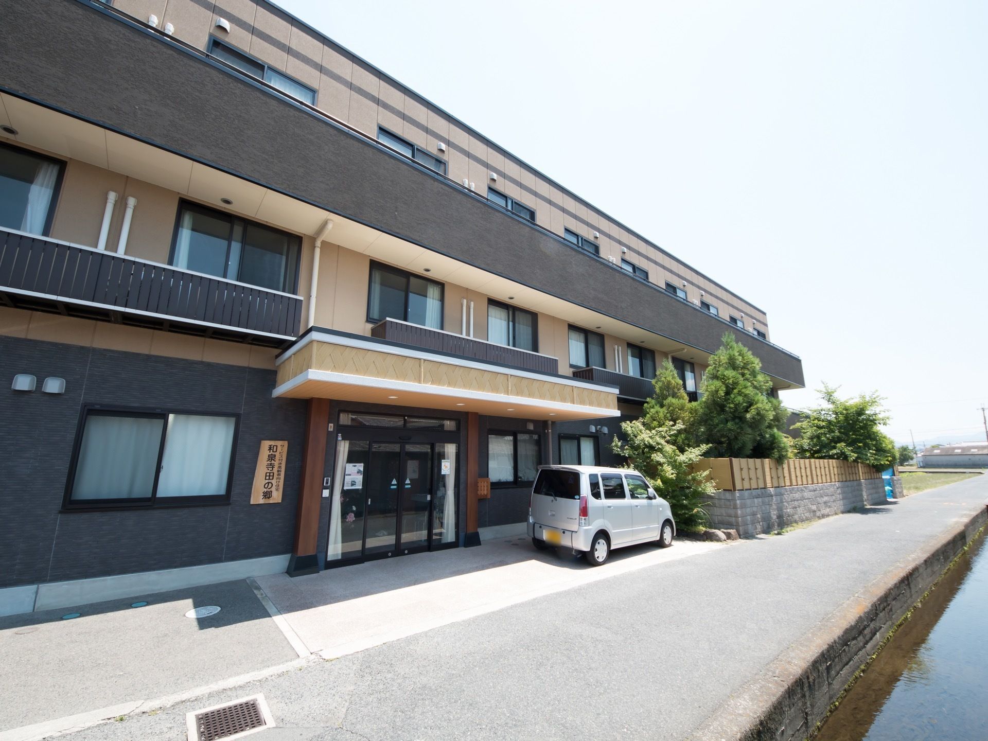 施設は３階建てである。１階部分や２,３階のベランダ壁はダークブラウンで、他の外壁はクリーム色である。