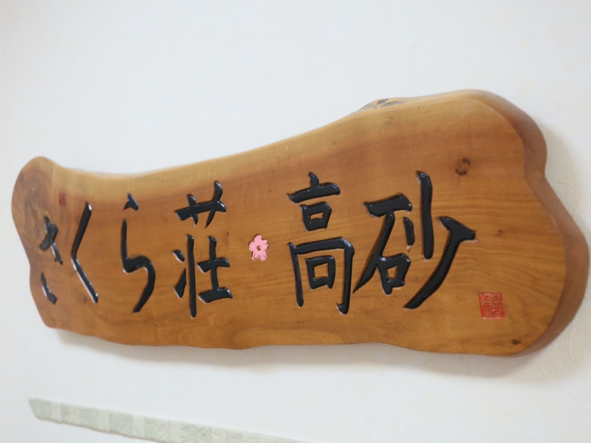 上質な木材を使用した、施設の看板が設置されてある。手書きで施設名が書かれており、あたたかい雰囲気がただよう。