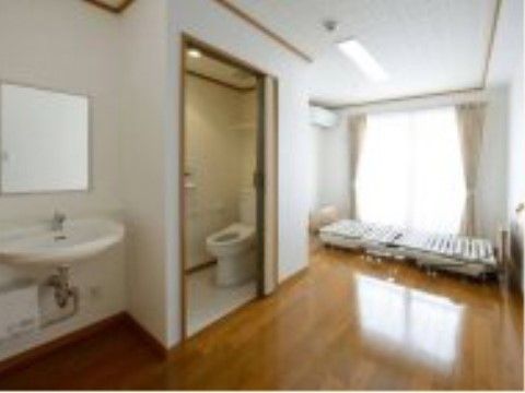 大きな窓の手前にリクライニングベッドが置かれ、洗面台とトイレのある個室